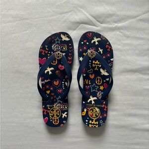 Tory Burch navy flip flops with a design and gold symbol